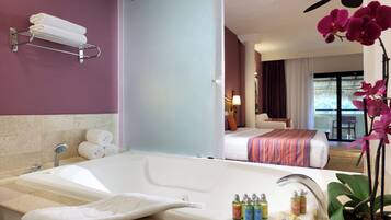 Un baño de hotel con una bañera grande, un perchero y artículos de aseo en el borde.