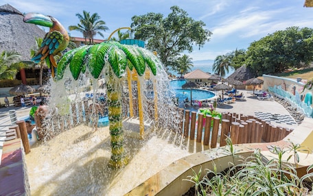 A water feature with a tropical design, a pool, and thatched-roof structures.