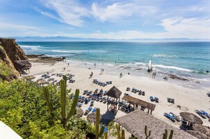 En la playa, sillas reclinables de playa, sombrillas, toallas de playa