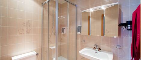 A modern bathroom with a glass-enclosed shower, a white sink, and a toilet.