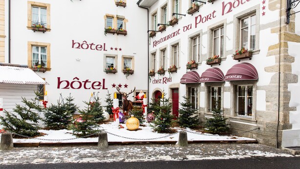 A hotel facade with multiple windows, some with flower boxes, and a Christmas display including a reindeer and trees. - Hôtel du Port (Estavayer-le-Lac)