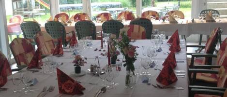 A dining area with a long table set for a meal, surrounded by chairs with patterned cushions.