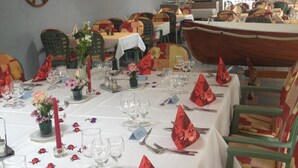 A dining area with tables set for a meal, chairs, and a large ship model in the background. - Hôtel du Port (Estavayer-le-Lac)