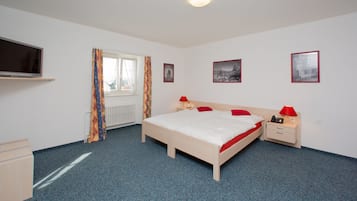 Una habitación de hotel con cama, mesitas de noche, televisión y cuadros en la pared.