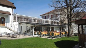 A restaurant with outdoor seating, a covered patio, and a staircase leading to an upper level. - Hôtel du Port (Estavayer-le-Lac)