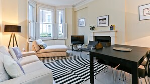 A modern living room with a sofa, a dining table, and a fireplace. - The Chelsea Apartment (London)