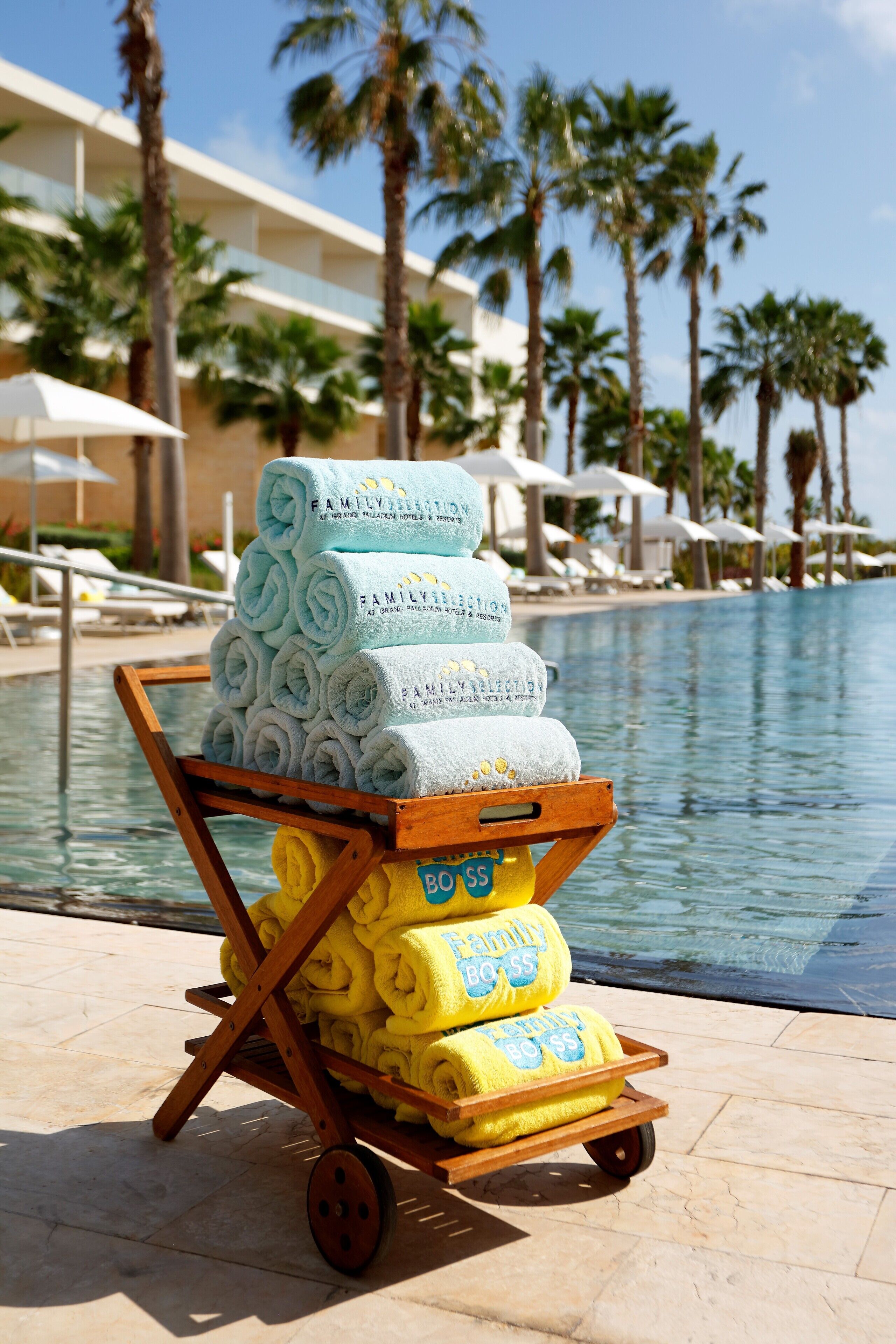 A poolside area with a cart of towels and a pool.