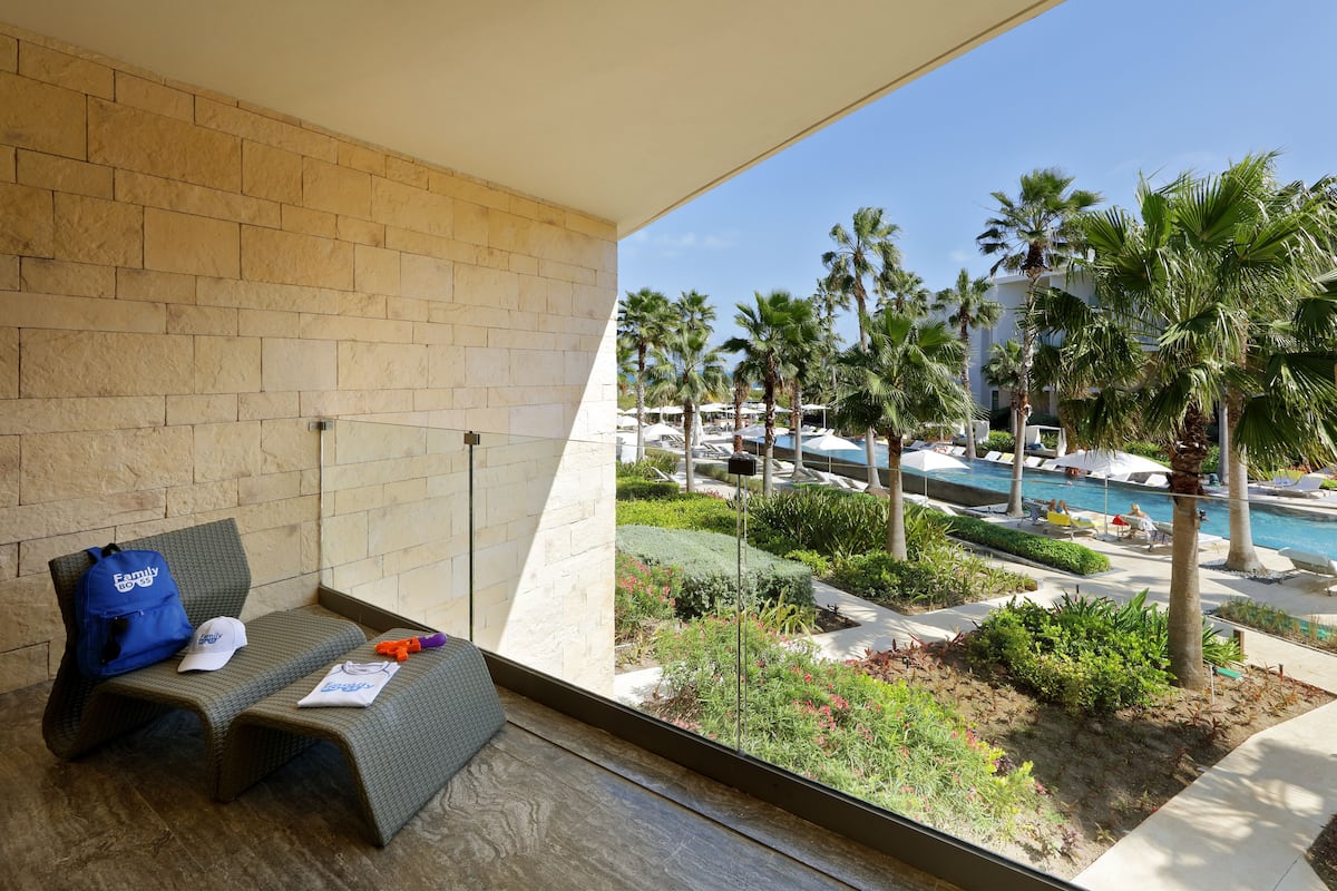 A balcony with a view of a pool, palm trees, and a brick wall.