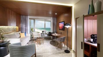 Ein modernes Hotelzimmer mit Sofa, Sesseln, Esstisch und Meerblick.