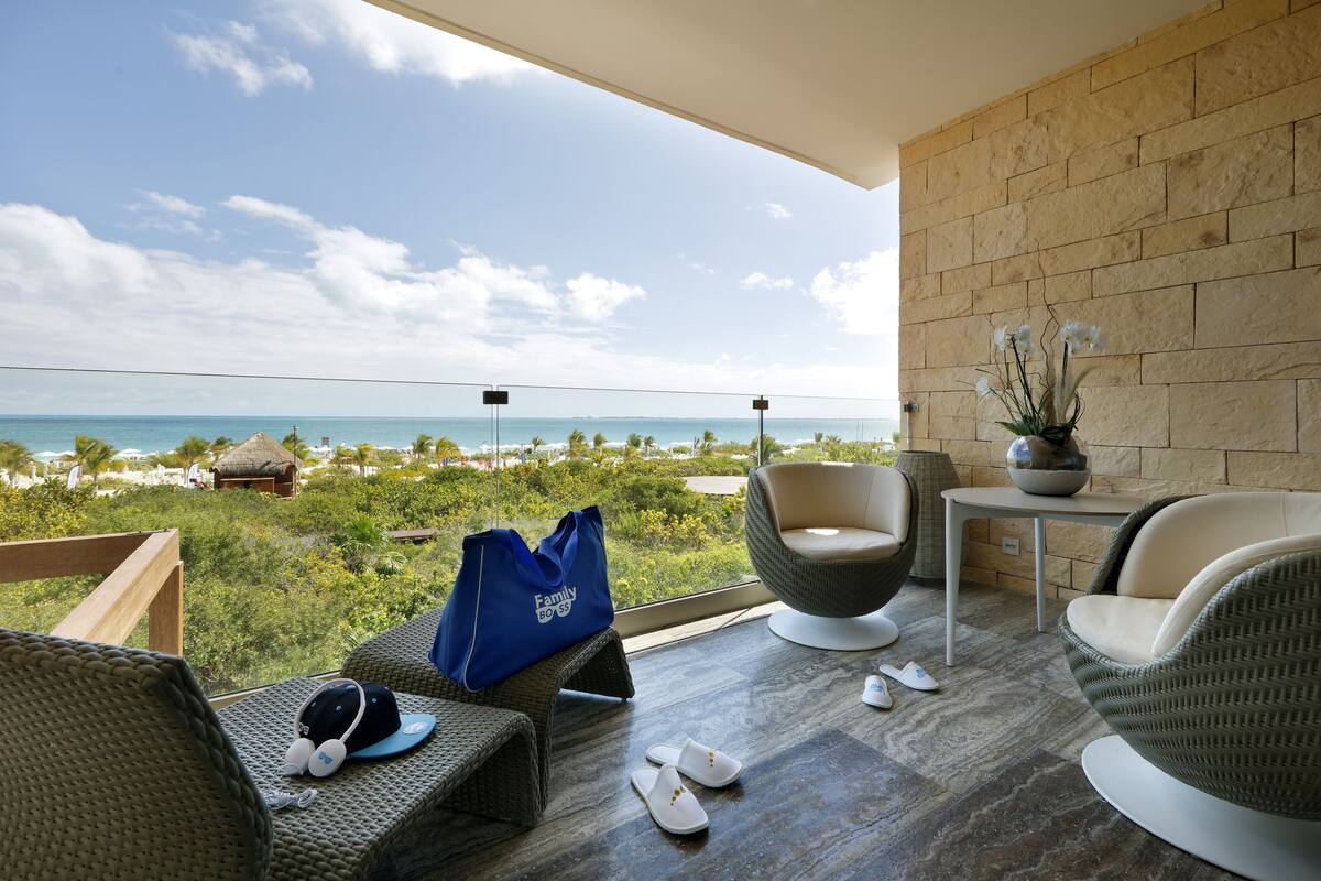 A balcony with wicker furniture, a blue bag, and a view of the ocean.