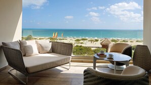 A balcony with a view of a beach, wicker furniture, and a table with a cup. - Family Selection at Grand Palladium Select Costa Mujeres - All Inclusive (Costa Mujeres)