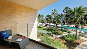 A balcony with a view of a pool area, palm trees, and a brick wall.