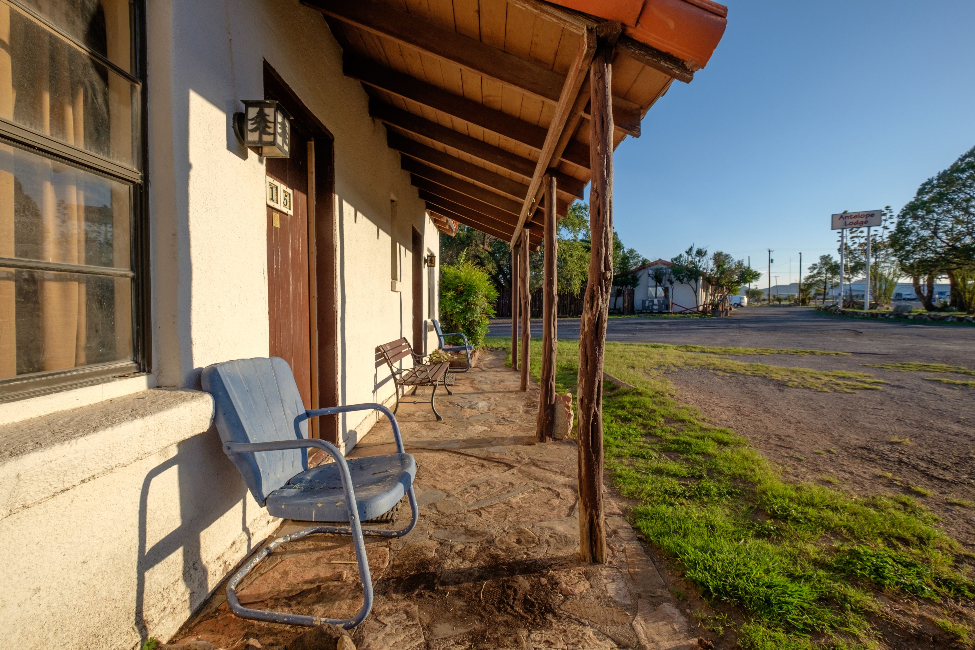 A building with a covered porch, a blue chair, and a stone pathway.