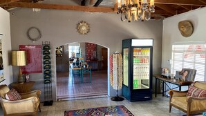 Una habitación acogedora con una araña, un refrigerador lleno de bebidas y una puerta que da a otra zona.