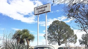 Un coche clásico turquesa aparcado frente a un cartel que dice 'Antelope Lodge'.