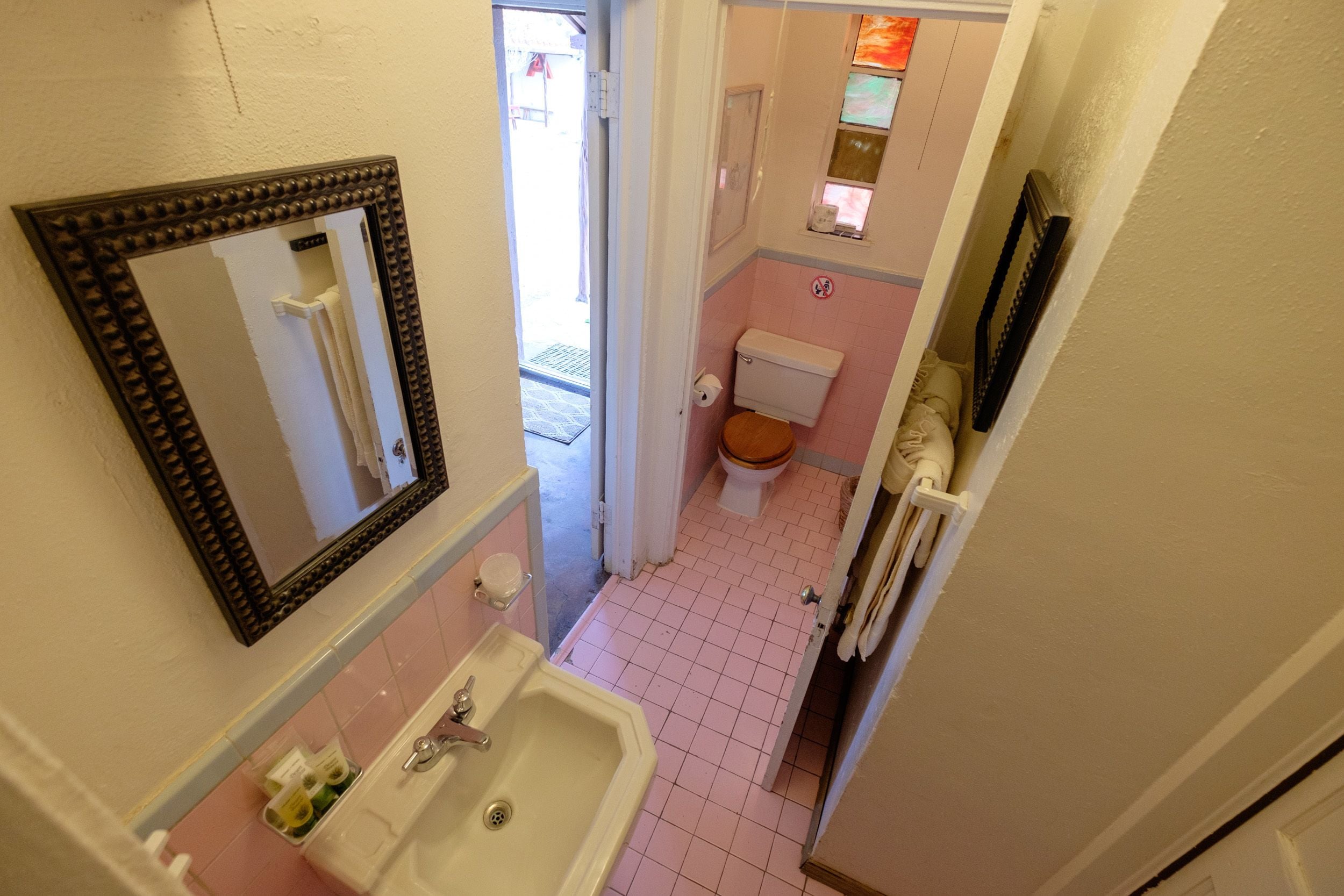 Une petite salle de bain comprenant un lavabo, un miroir, des toilettes et une petite fenêtre.