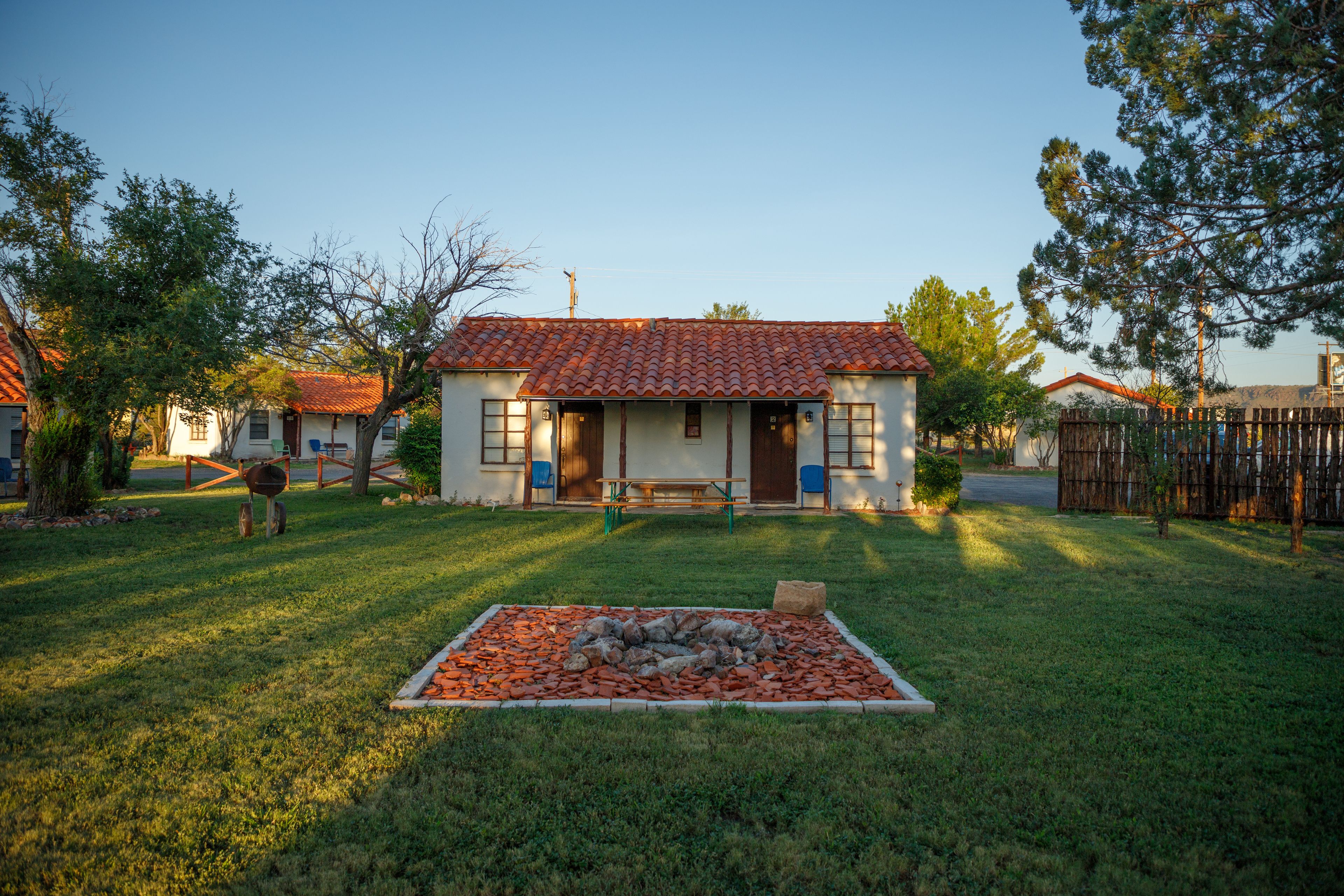 A house with a tiled roof, a front porch, and a fire pit in the yard.