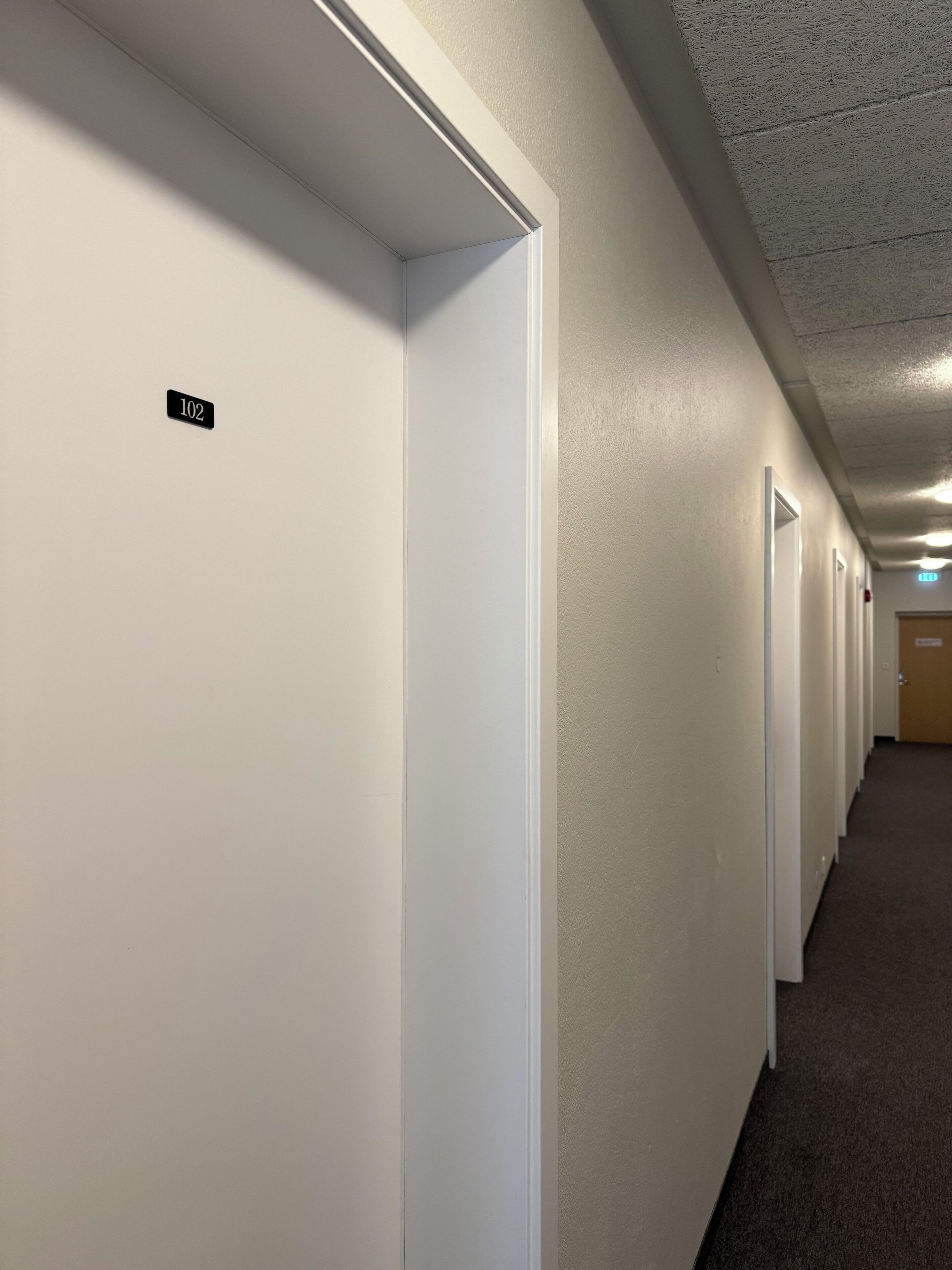 A hallway with white doors, each marked with a number.