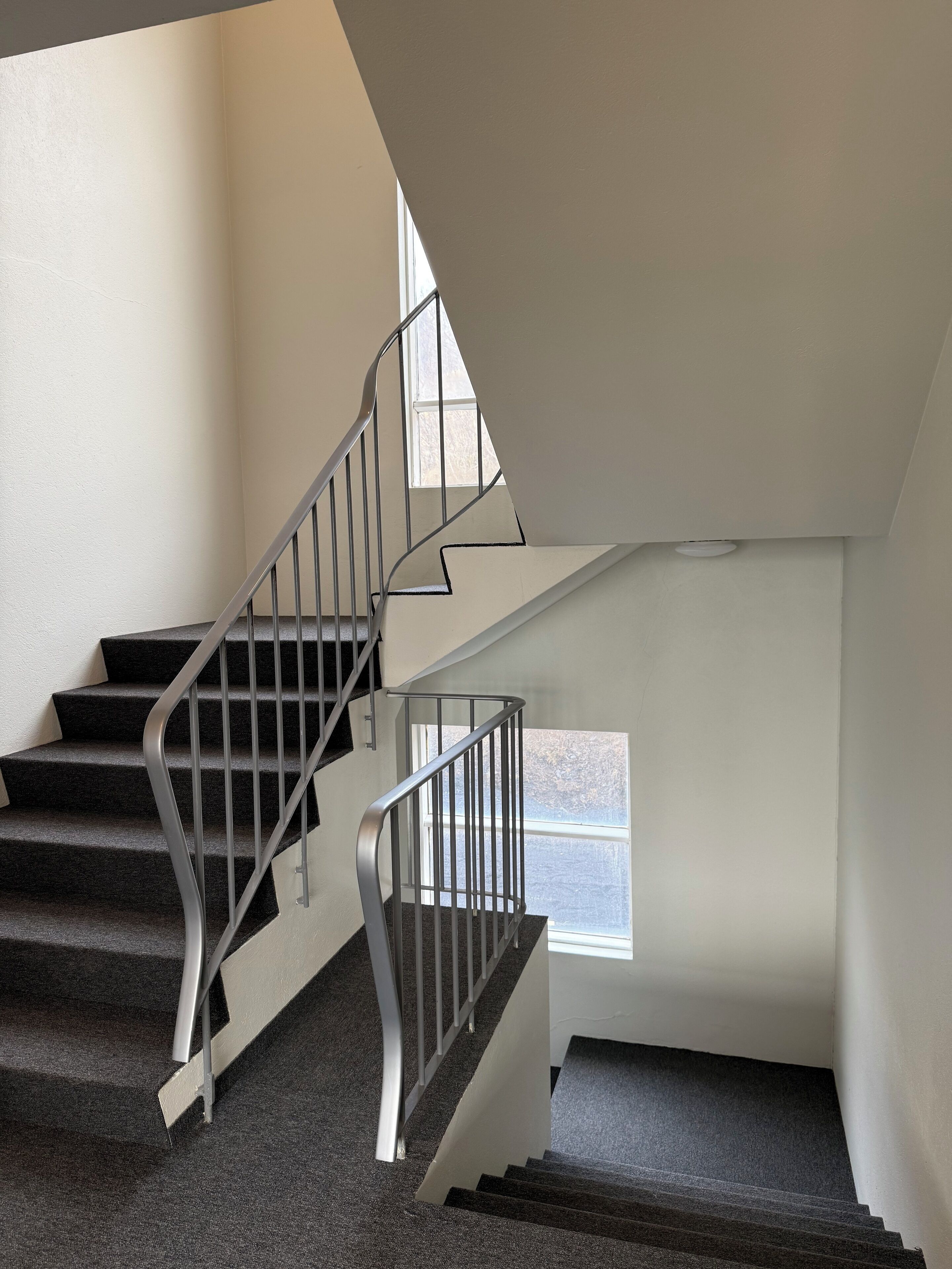 A staircase with metal railings and carpeted steps leading to a landing.