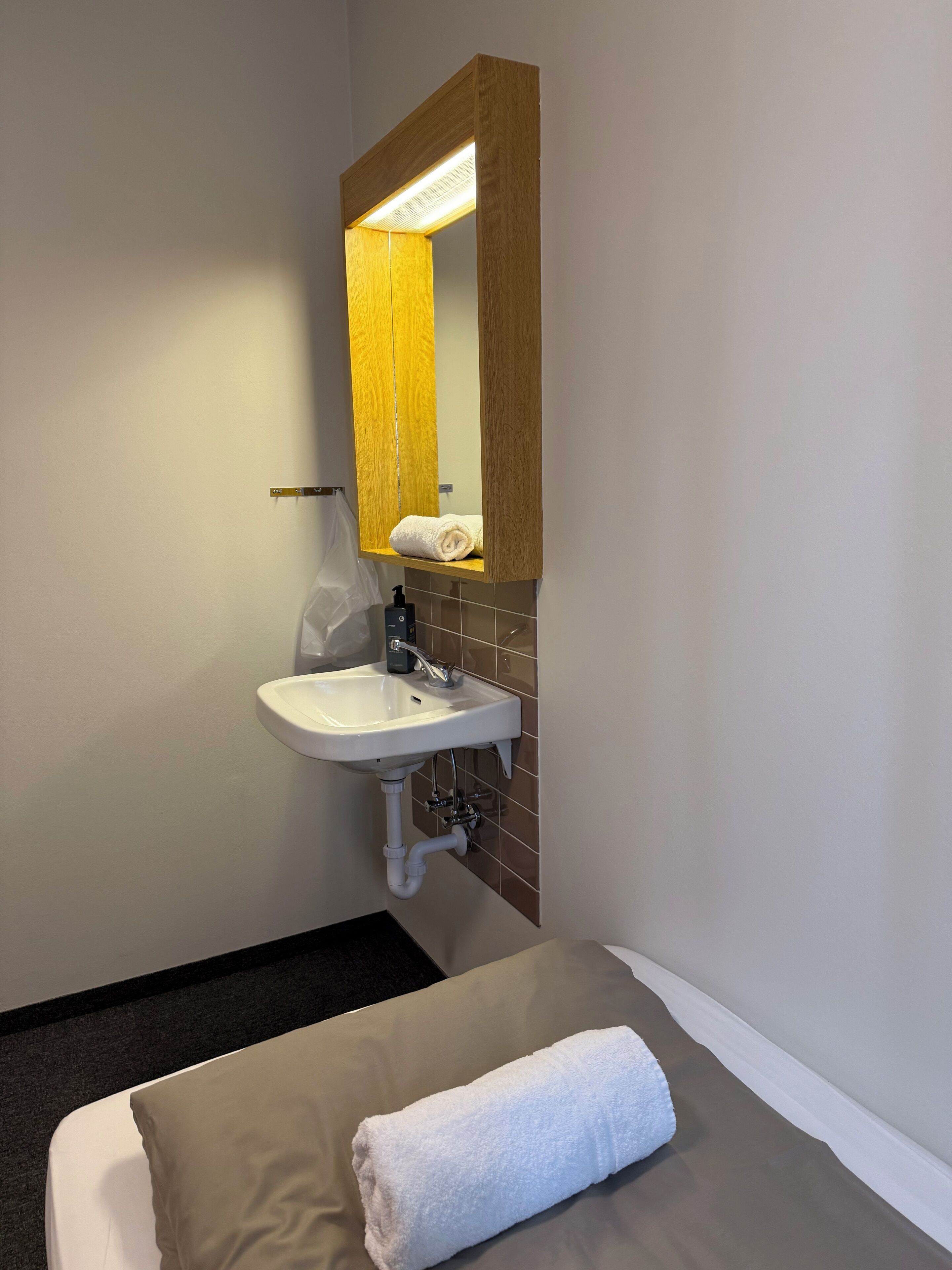Un baño con un lavabo blanco, un espejo y una toalla sobre la cama.