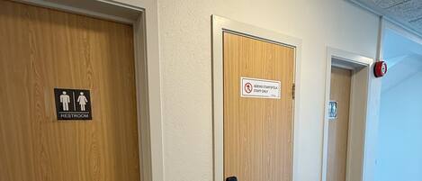 A hallway with three doors, one marked for staff use, another for restrooms, and a third door leading to a room.