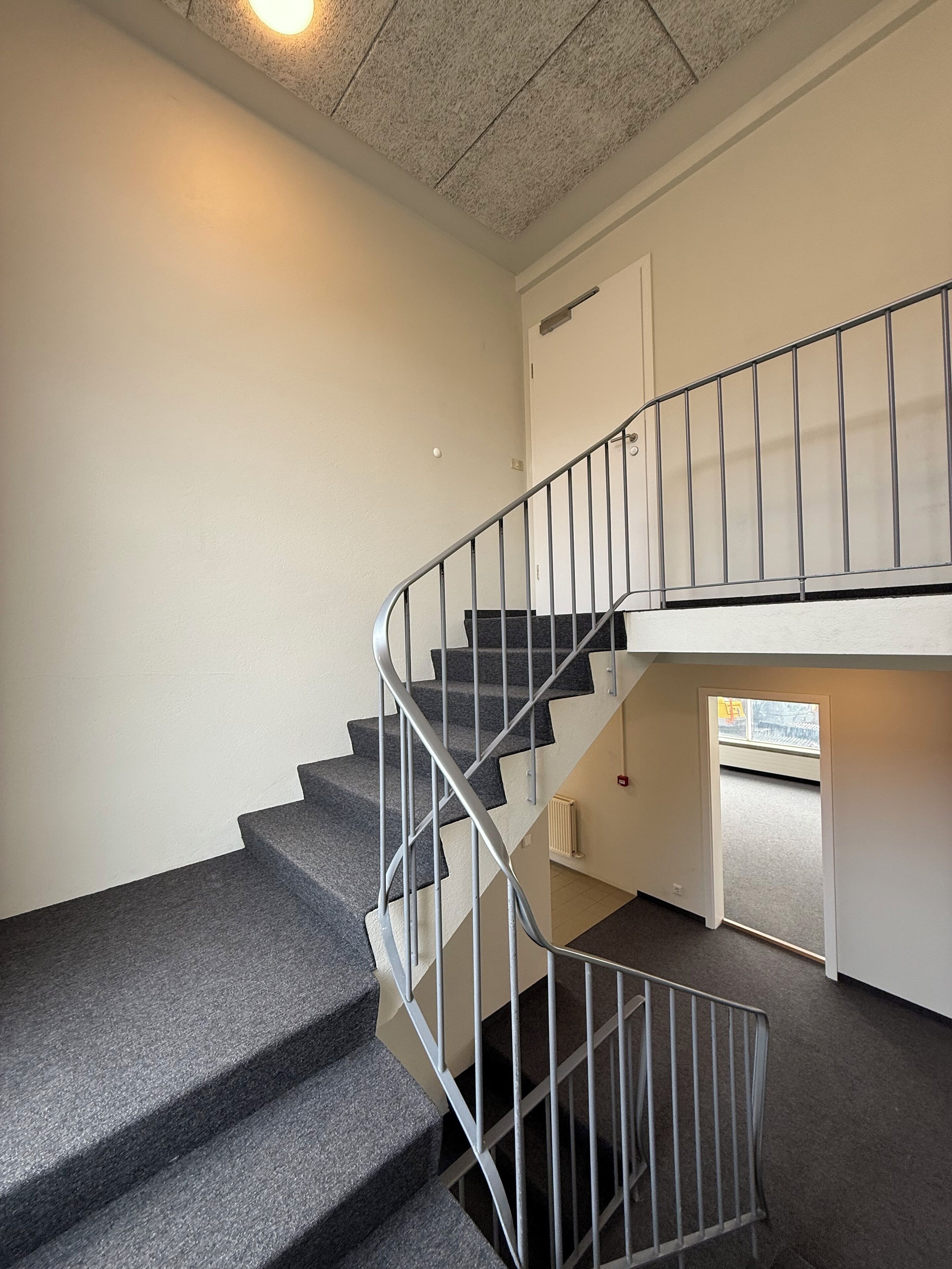 Una escalera con barandales de metal que sube a un piso superior.