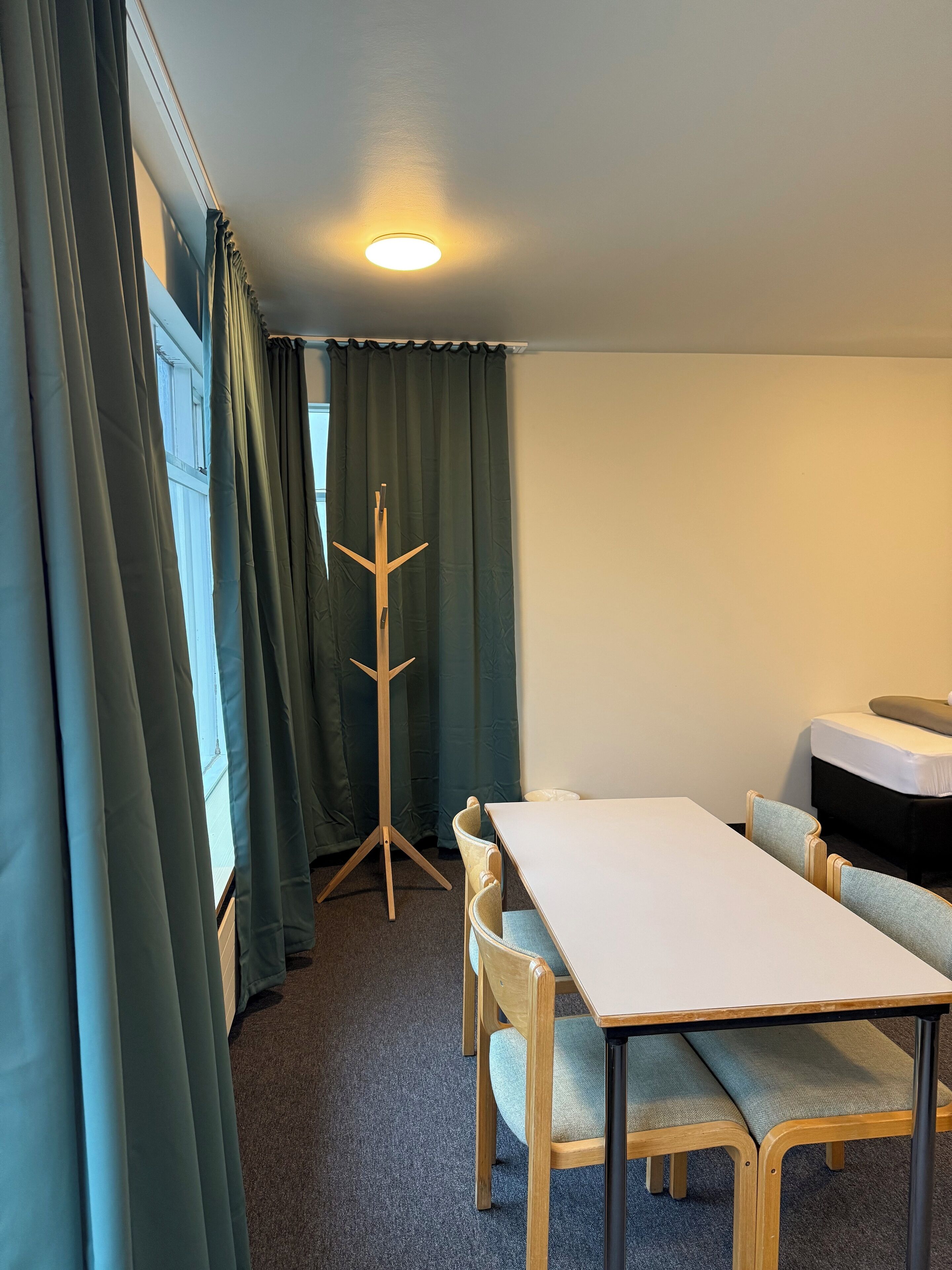 Une pièce comprenant une table et des chaises, un porte-manteau et un lit.
