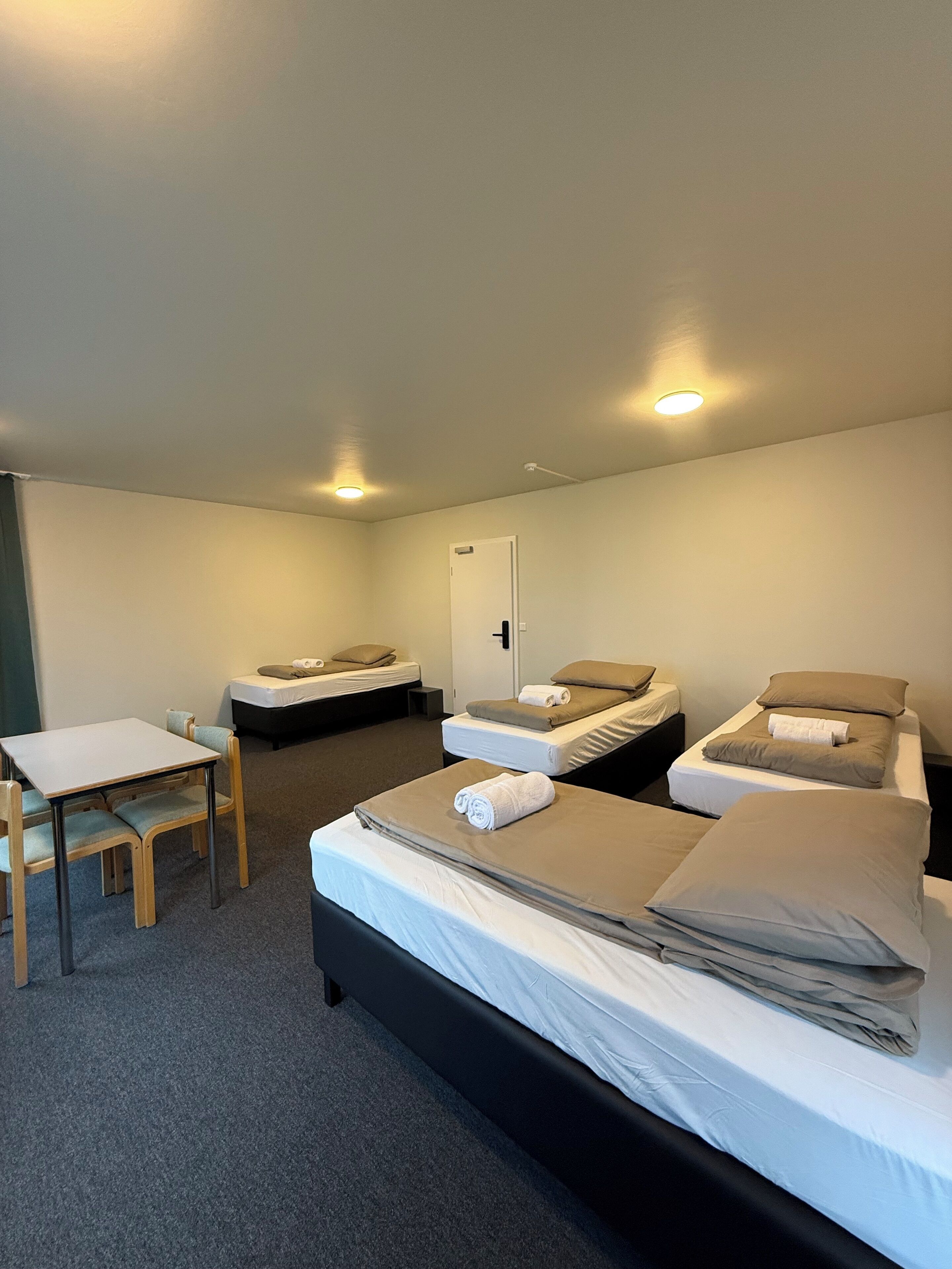Een hotelkamer met twee eenpersoonsbedden, een tafeltje en een stoel.