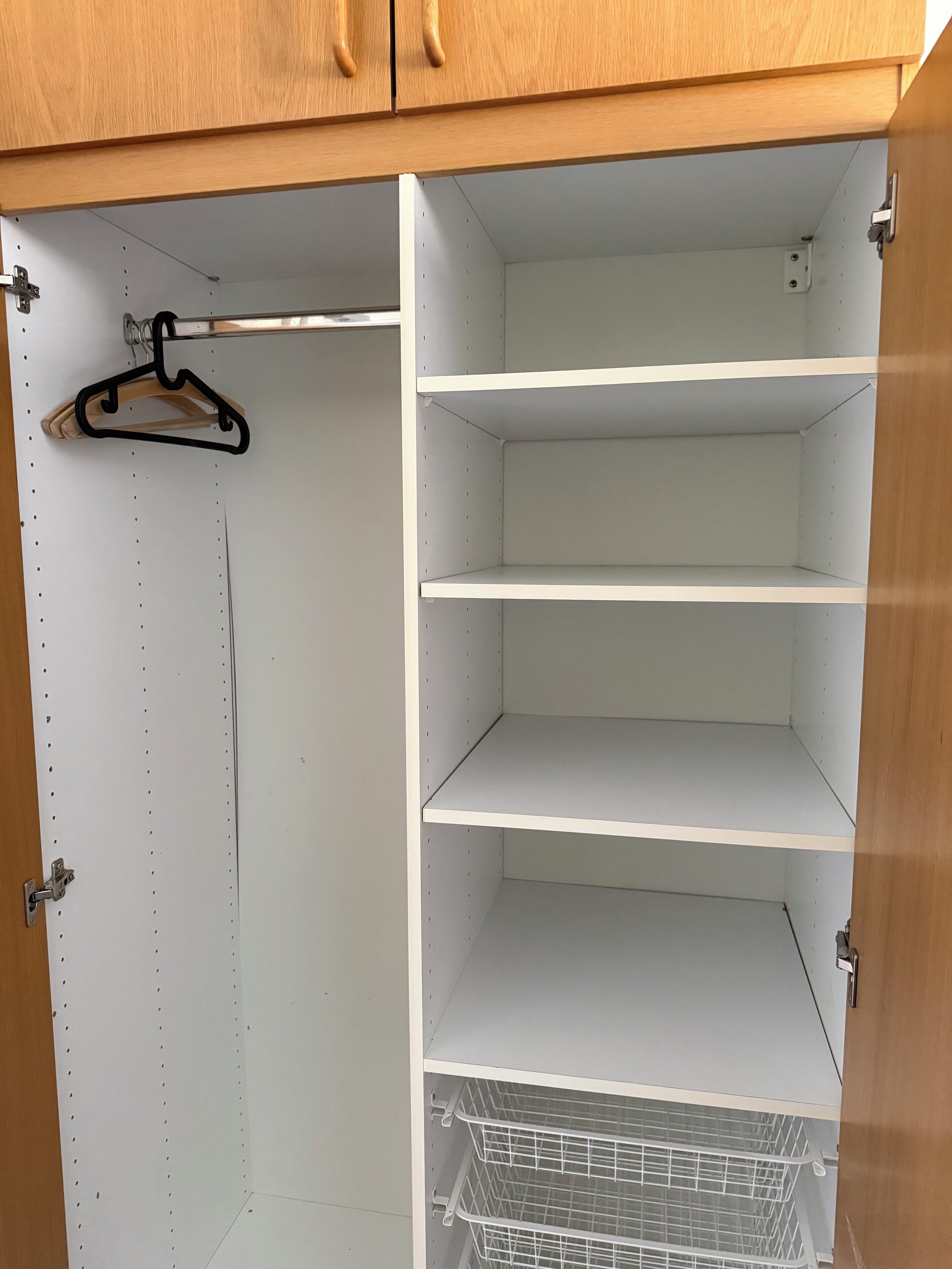 Un placard avec trois étagères ouvertes et une tringle pour suspendre les vêtements.