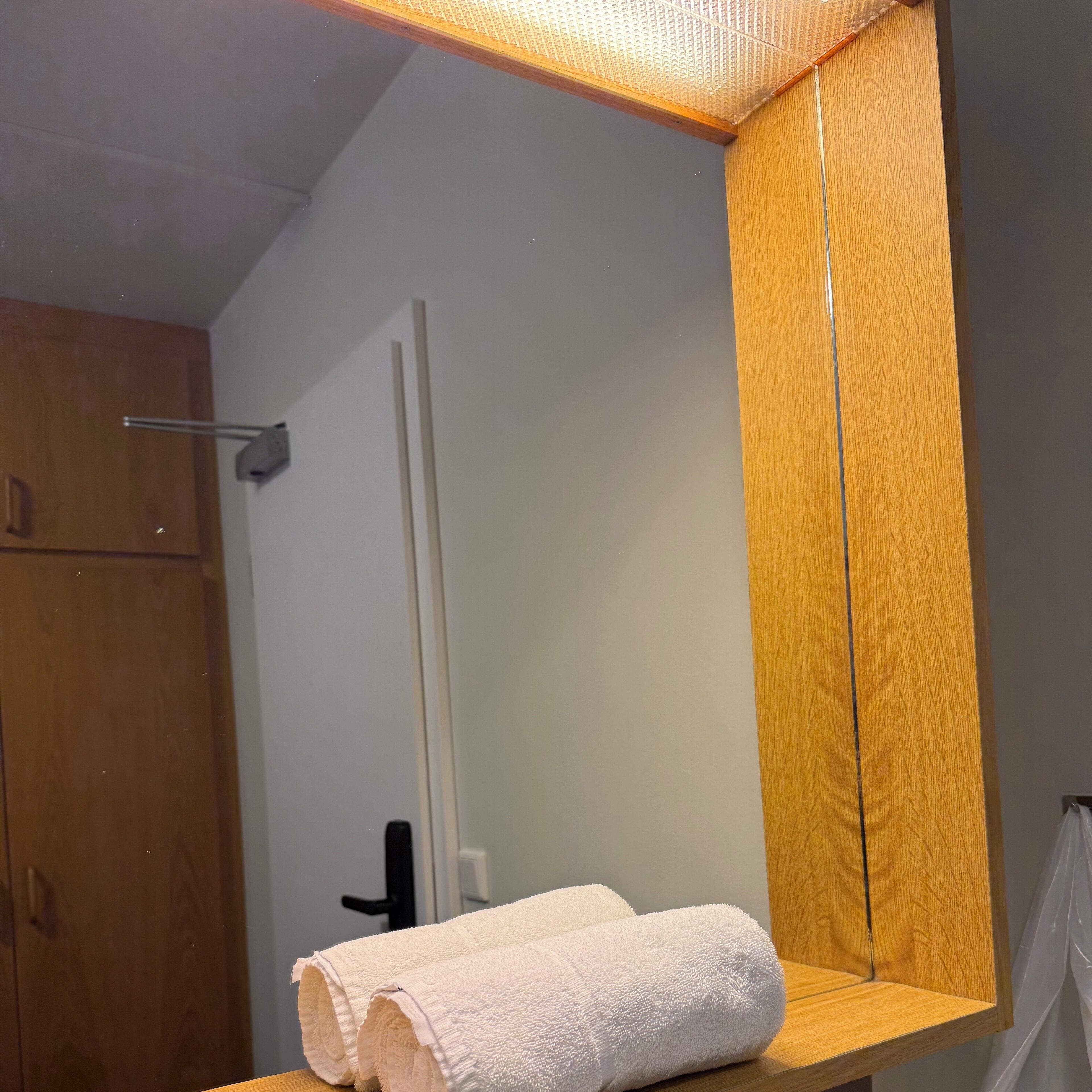 Un baño con tocador de madera, una toalla y un espejo.