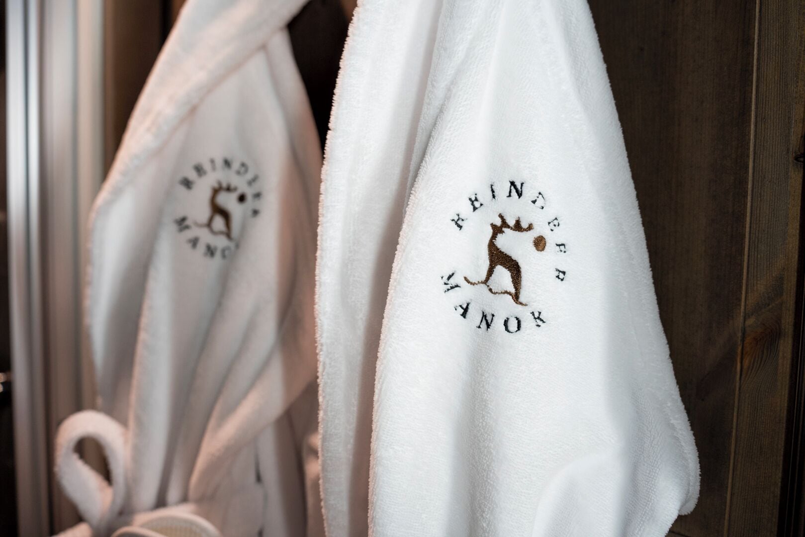 A rack of white robes with embroidered text and a kangaroo logo.