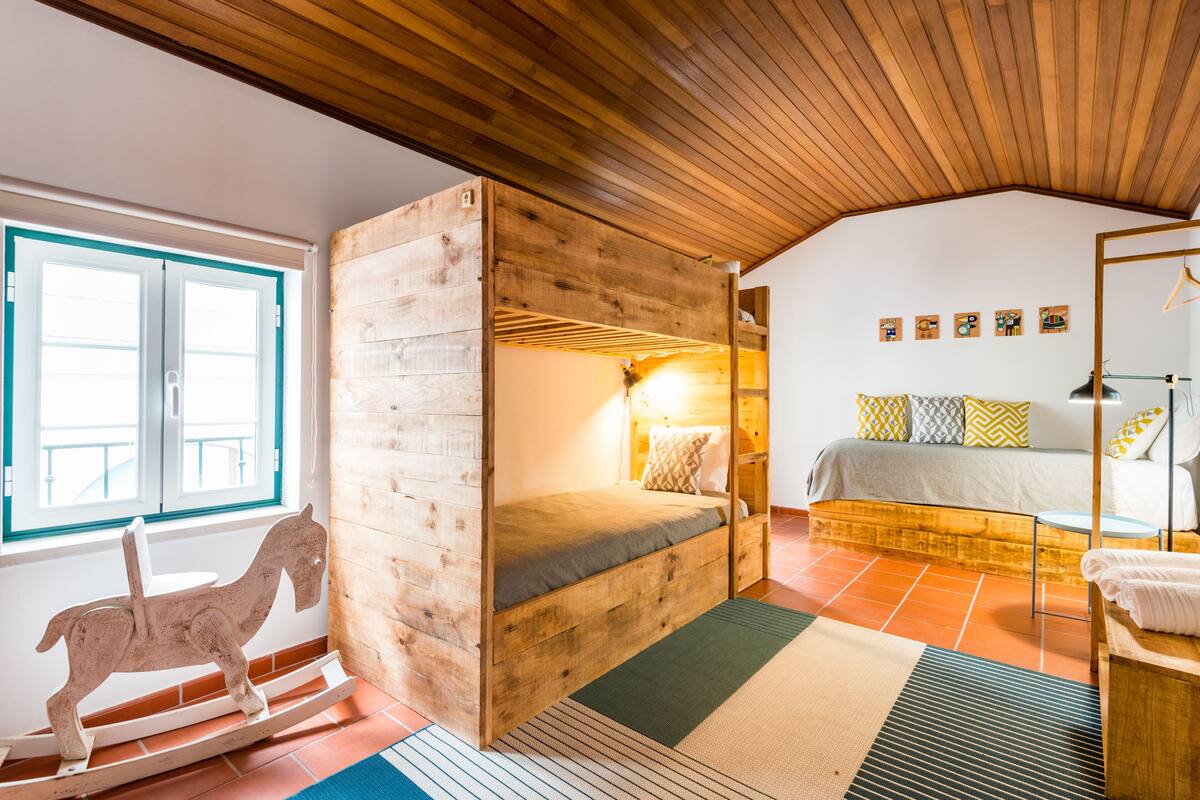 A cozy room with a bunk bed, a rocking horse, and a window with a view.