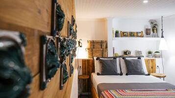 A cozy bedroom with a wooden headboard, a bed with a colorful blanket, and a small wooden stool.