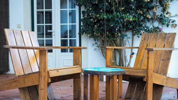 Two wooden chairs and a small table outside a building with a white door and a window.
