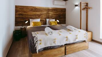 A bedroom with a wooden headboard, two bedside tables with lamps, a hanging coat rack, and a large window.