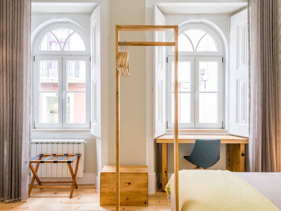 Een kamer met een houten bureau, een stoel, een bed en een droogrek.