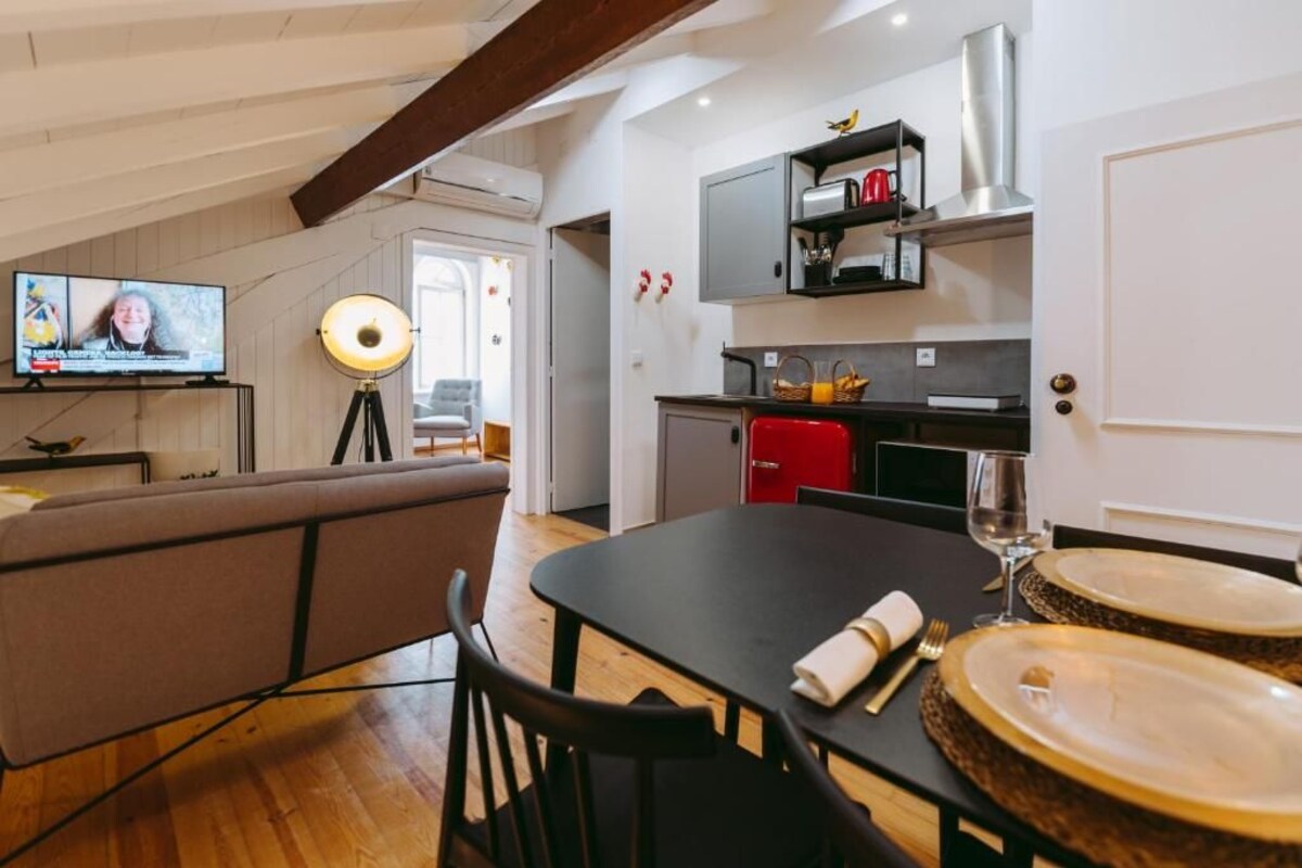 A modern kitchen with a dining area, a TV, and a sofa.
