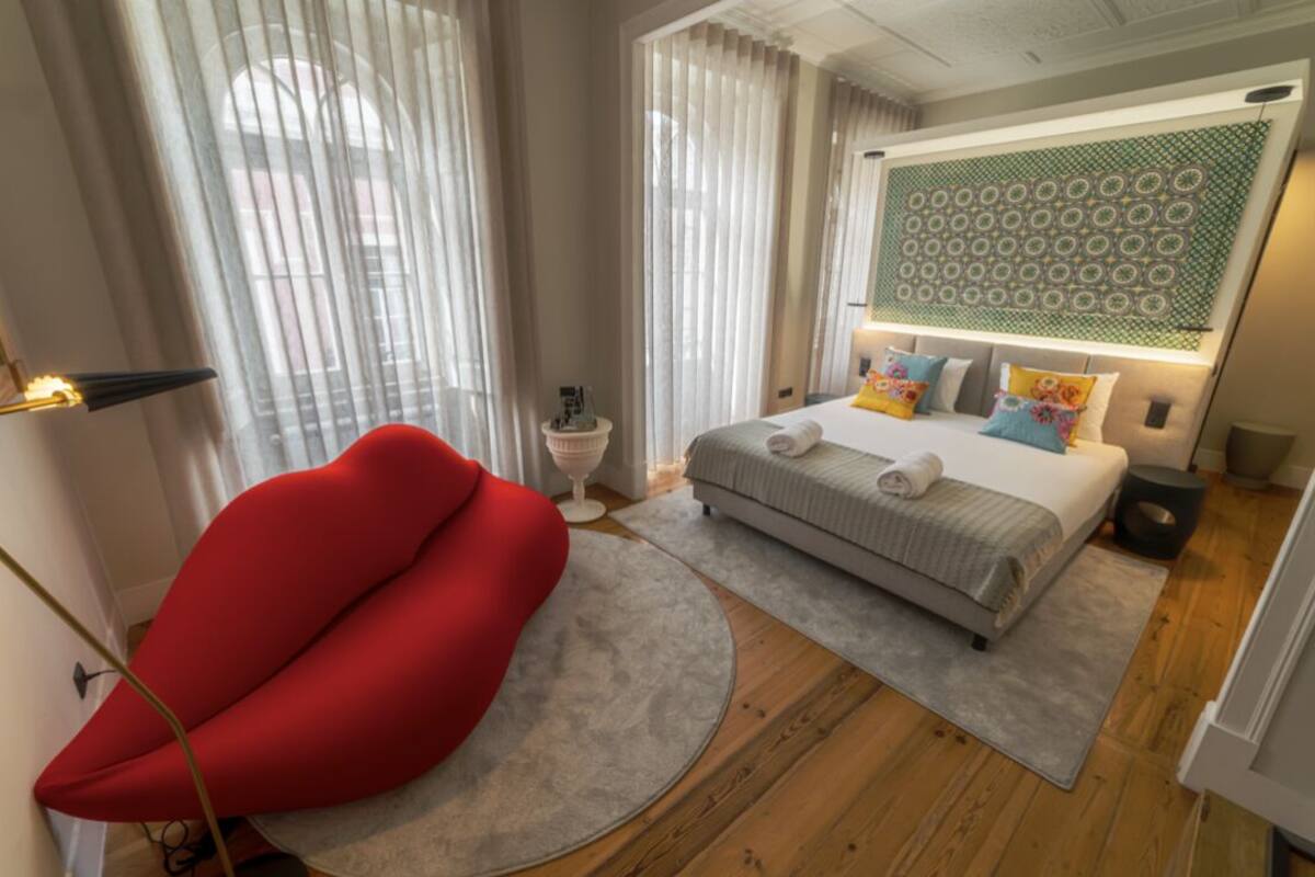 A modern bedroom with a bed, a red chair, and a decorative wall panel.