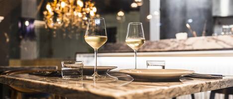 A dining table with two wine glasses and a water glass, set in a restaurant with a chandelier in the background.