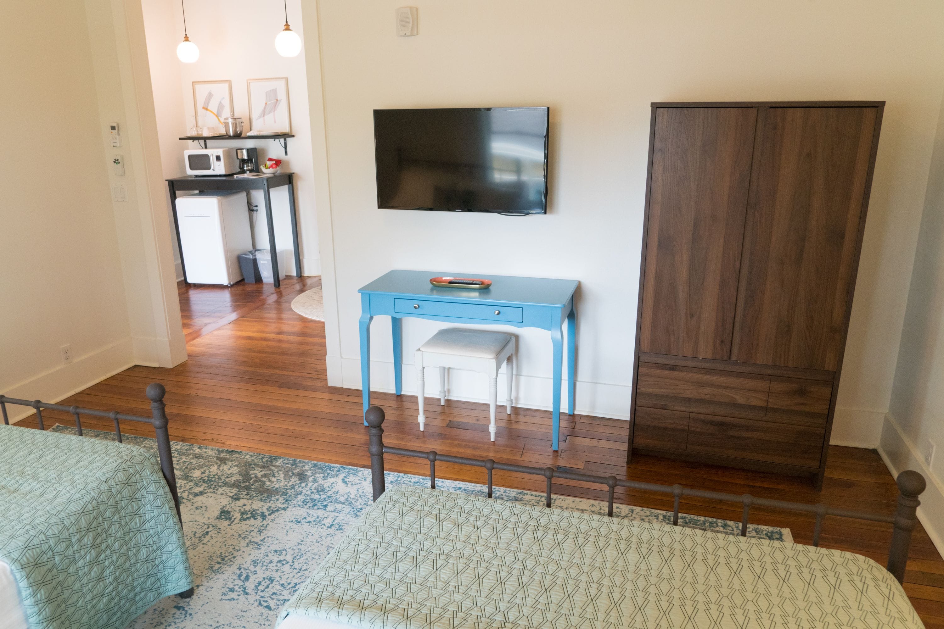 A bedroom with a bed, a desk, a chair, a TV, and a wardrobe.