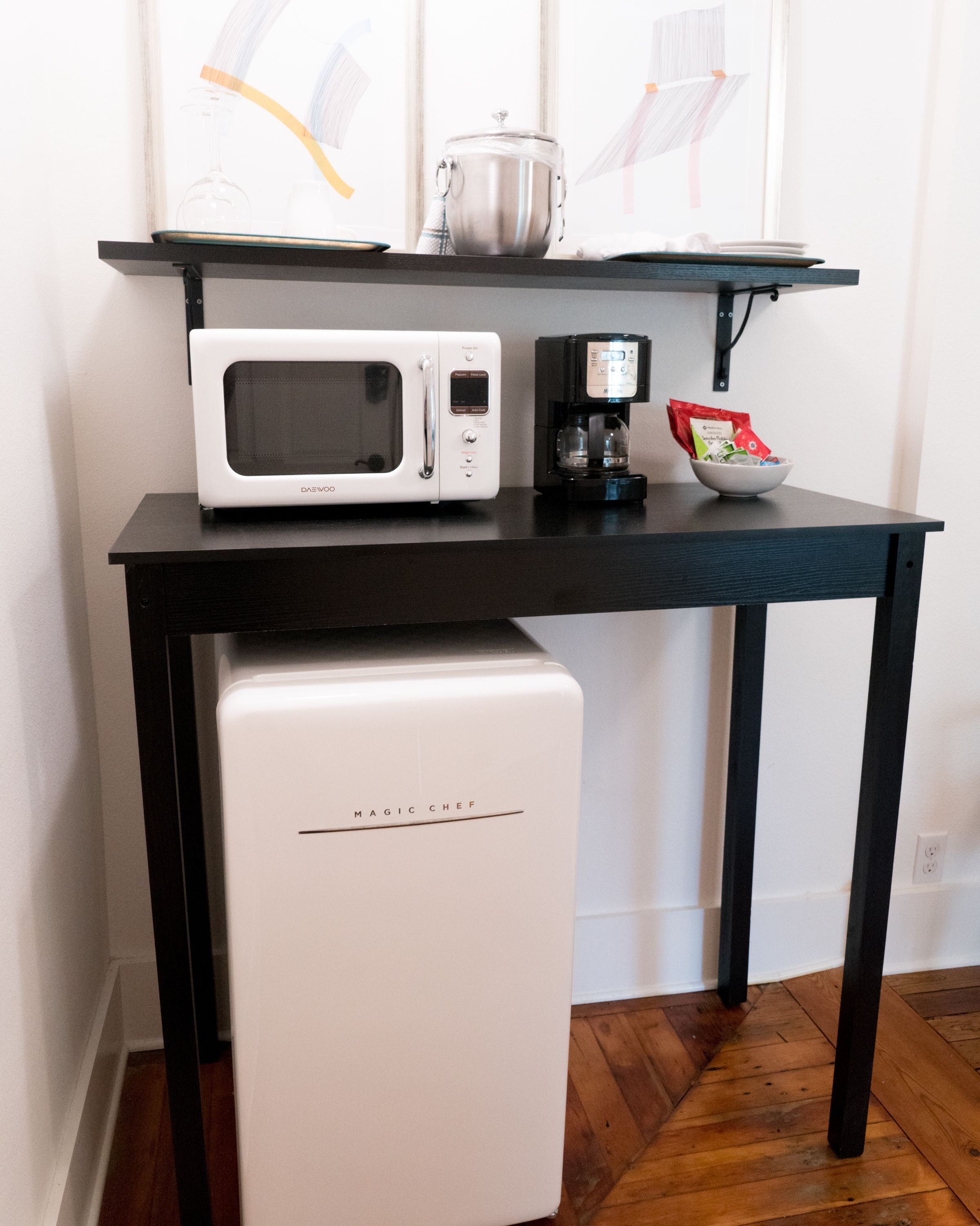 Cocina compacta con microondas, cafetera y refrigerador pequeño.