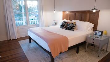 Une chambre à coucher bien rangée, avec un grand lit, une table de chevet, une commode et une fenêtre avec des rideaux.