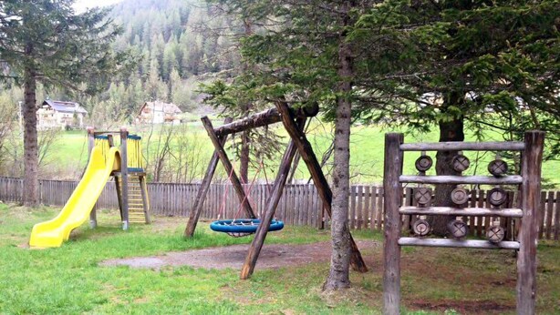 A playground with a yellow slide, a swing set, and a tire swing. - Alpina Mountain Resort (Stelvio)