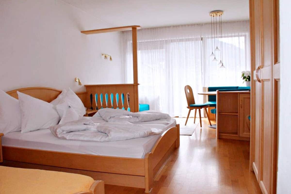 A bedroom with a wooden bed, a desk, and a chair.