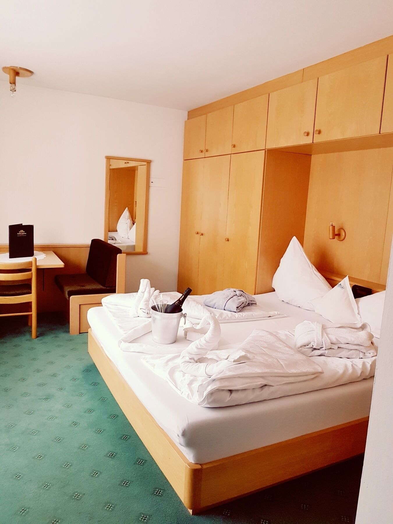 Ein Hotelzimmer mit Bett, Schreibtisch, Stuhl, Spiegel und Kleiderschrank.
