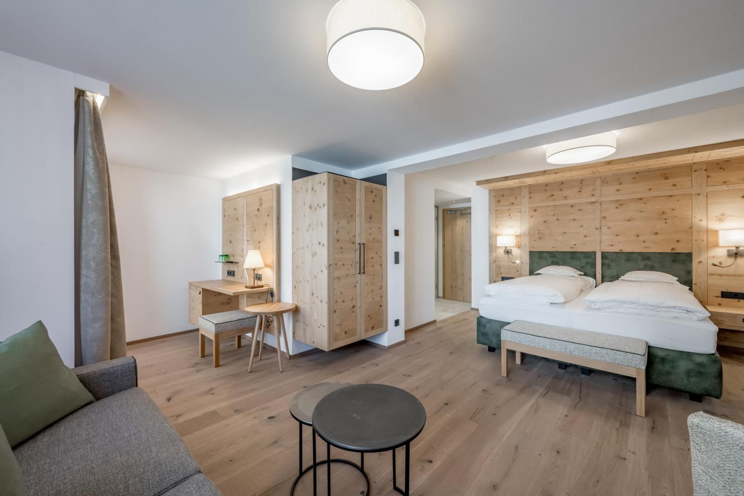 A hotel room with a bed, a desk, a chair, and a small table.