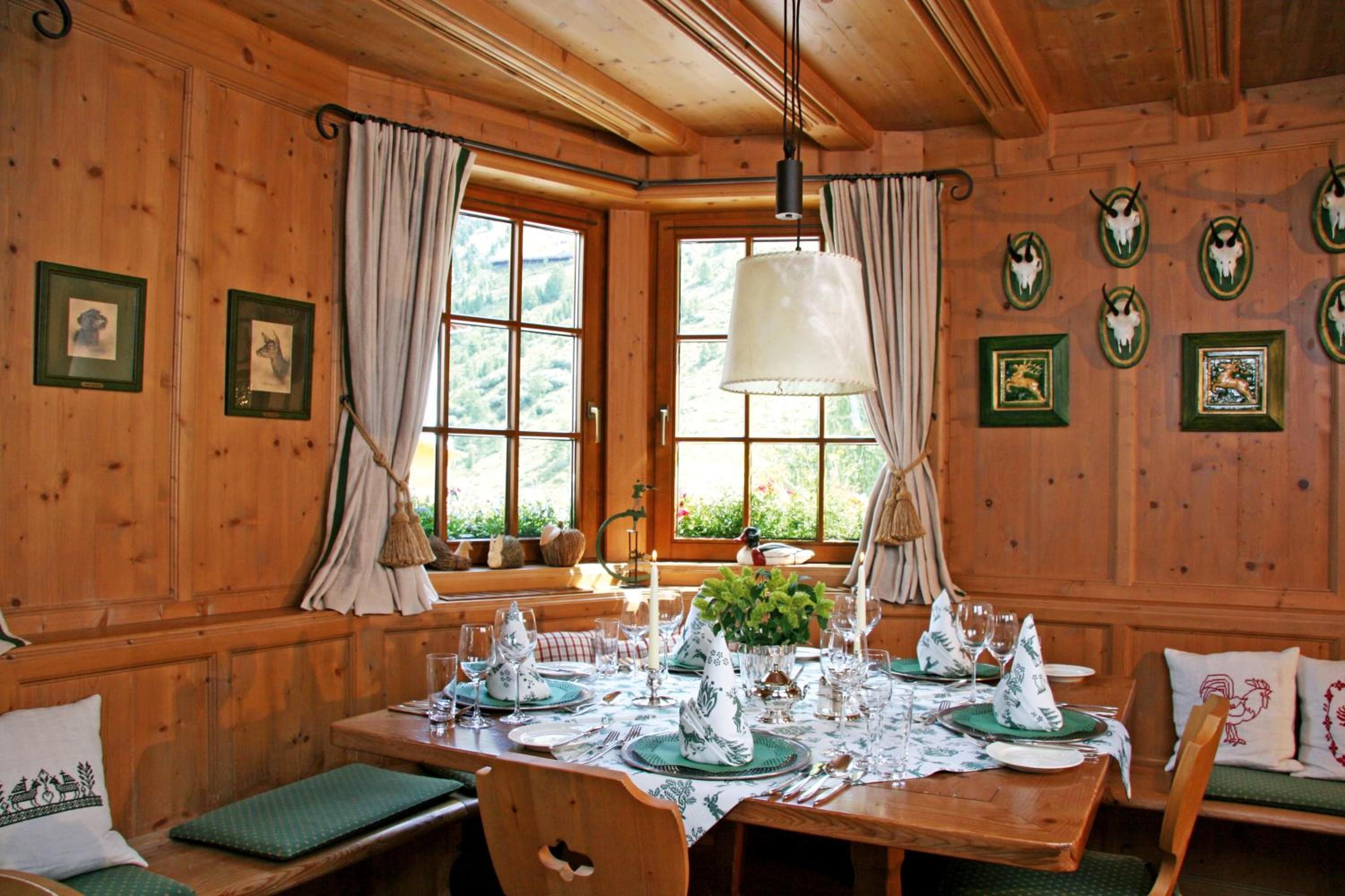 A wooden dining room with a table set for four, large windows, and wall-mounted animal skull decorations.