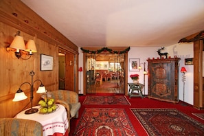 A cozy room with a wooden interior, a dining area in the background, and a red carpet.