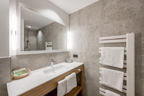 A modern bathroom with a white sink, mirror, and towel rack.