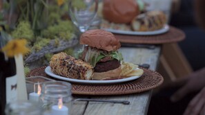 Una comida con una hamburguesa y papas fritas sobre una mesa con una vela y un florero con flores.